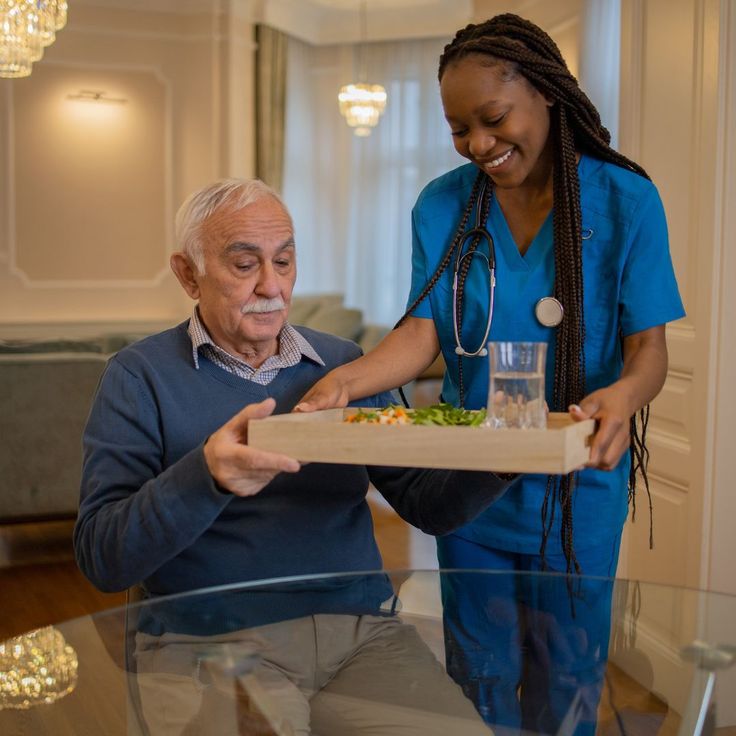 A carer supporting a client at mealtime, reflected in an up-to-date care plan